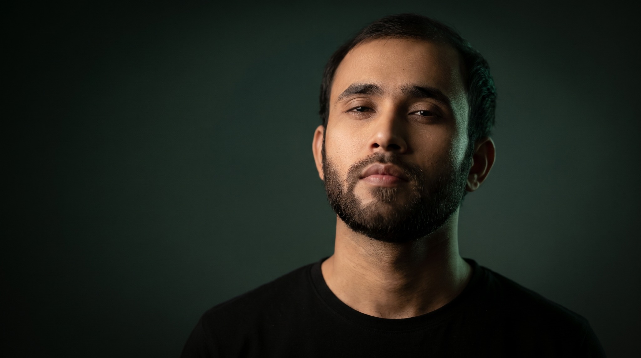 Rizwan Ali in a black shirt against a dark green background